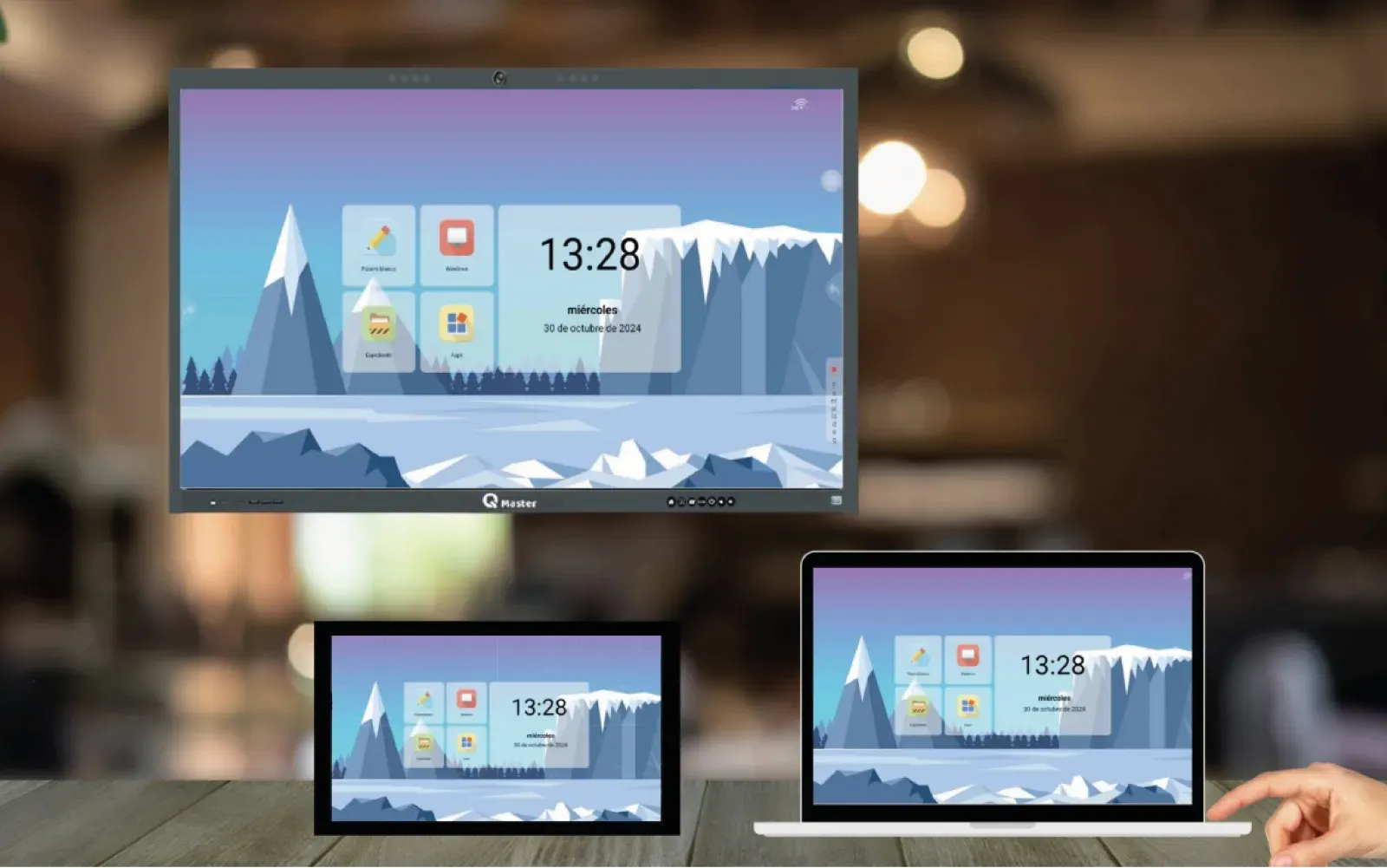 La misma pantalla de inicio de un panel QMaster duplicada en tres equipos a la vez: el panel montado en la pared, una tableta y un portátil sobre la mesa.