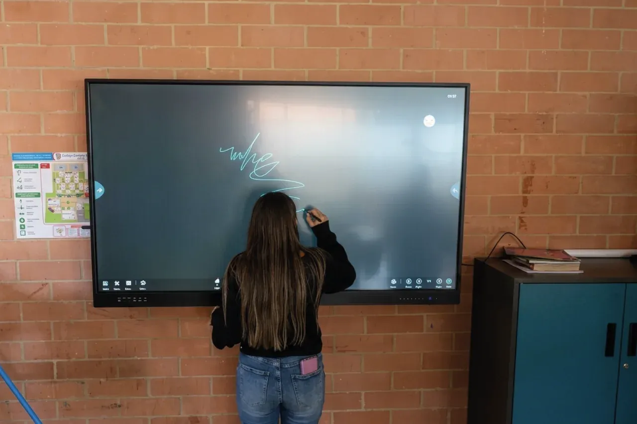 Una estudiante escribe sobre la pantalla interactiva instalada en el aula de un colegio público de Bogotá.