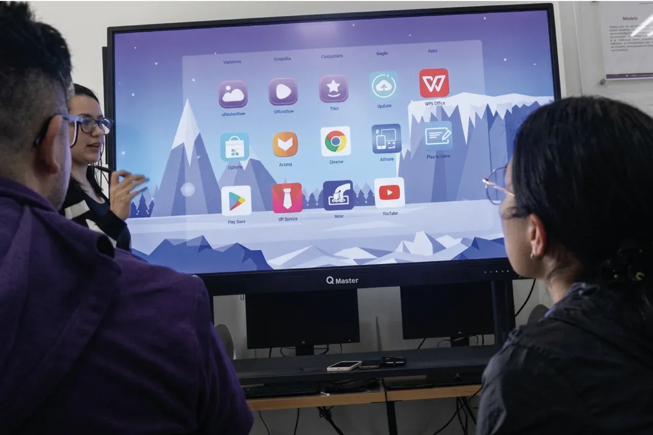 Pantalla interactiva QMaster encendida en su escritorio de aplicaciones durante una actividad de la biblioteca, con asistentes frente a ella.
