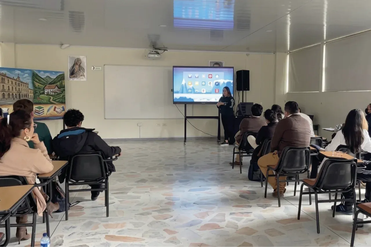 Clase en curso en el salón: los estudiantes trabajan desde sus puestos con el contenido proyectado en la pantalla interactiva del aula.