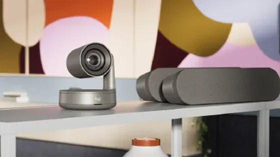 Primer plano de una cámara PTZ y una barra de video Logitech montadas sobre un mueble de sala