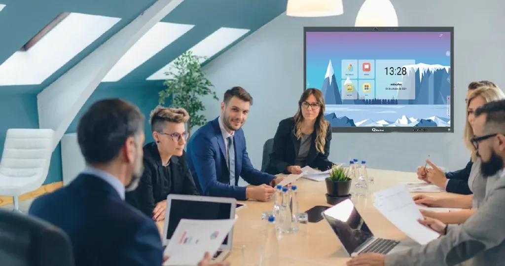 Sala de reuniones con una pantalla interactiva QMaster encendida frente a la mesa de trabajo